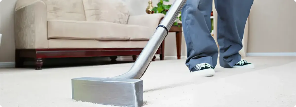 Carpet cleaning technician using a hot-water extraction wand on a light-colored carpet in a living room, Portland, OR.